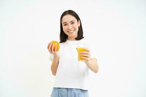 porträtt av skön ung kvinna med friska passa diet, drycker juice från färsk pressas orange frukt, vit bakgrund foto