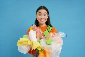 leende koreanska kvinna, återvinning, innehav plast avfall och sortering den för återvinna Centrum, blå bakgrund foto