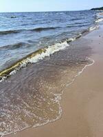 en sandig strand med vågor och vatten foto