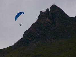 en person flygande en paraglider över en berg foto