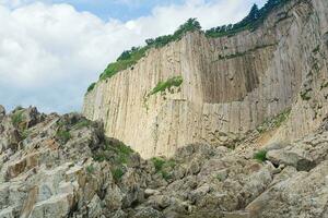 hög kust klippa bildas förbi sten kolumner, cape stolbchaty på de ö av kunashir foto