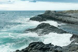 klippig havsstrand sammansatt av pelar- basalt mot de stormig hav, kust landskap av de kuril öar foto