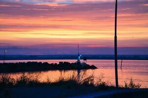 solnedgång i Sverige på de hamn av sjö vaettern. fyr i de bakgrund foto