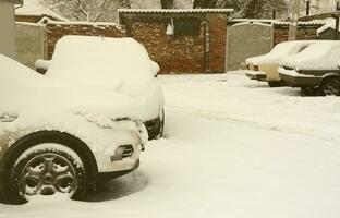 fragment av de bil under en lager av snö efter en tung snöfall. de kropp av de bil är täckt med vit snö foto