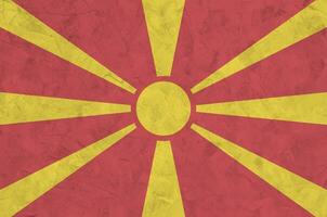 macedonia flagga avbildad i ljus måla färger på gammal lättnad putsning vägg. texturerad baner på grov bakgrund foto