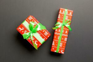 insvept jul eller Övrig Semester handgjort närvarande i papper med grön band på svart bakgrund. närvarande låda, dekoration av gåva på färgad tabell, topp se foto