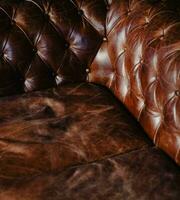 brun läder klädsel av de typisk chester soffa foto