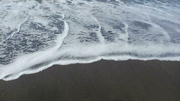 grå sand strand med mild vågor. tropisk strand. foto
