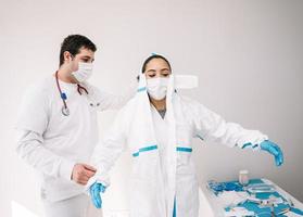 läkare som hjälper kollegan med att ta av sig kostym under covid foto