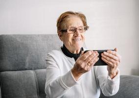 leende äldre kvinna med videosamtal på smartphone foto