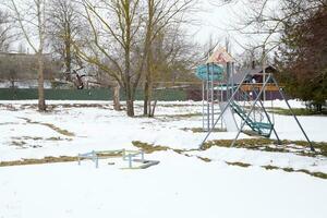barns lekplats i vinter- under snö. gunga, karusell och glida. vinter- ödslighet foto