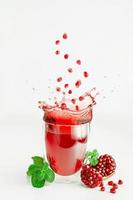 granatäpplefrön som flyger över stänkande juice i ett glas. hälsosam livsstil koncept. foto