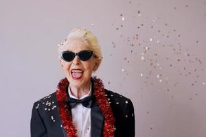 vacker snygg mogen äldre kvinna i solglasögon och smoking som firar nytt år. kul, fest, stil, firande koncept foto