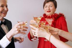 nytt år firar händer med glas vitt mousserande vin. jul, familj, vänner, firar, nyårskoncept foto