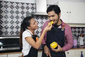 glada och leende unga par som lagar mat i köket hemma foto