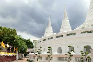 vit pagoder i kurva rad och grå molnig himmel, wat prayurawongswat Bangkok, thailand. foto