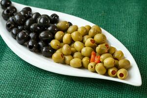 grön och svart oliver på en vit tallrik foto