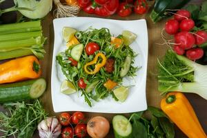 friska äter bakgrund. annorlunda grönsaker och sallad med blad grönsaker och körsbär tomater på vit tallrik. foto