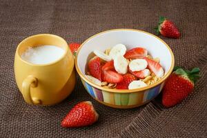 friska frukost. flingor, färsk jordgubbar, banan och mjölk foto