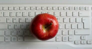 äpple av kunskap begrepp. perfekt mogen äpple frukt på vit defocused bärbar dator tangentbord topp se foto