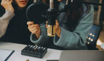 kvinna inspelning en podcast på henne bärbar dator dator med hörlurar och en mikroskop. kvinna podcaster framställning audio podcast från henne Hem studio. foto