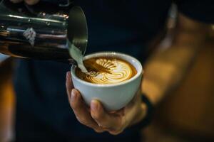 närbild av händer barista göra latte kaffe konst färg foto