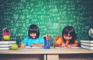 två flickor med krita ritning på lektion i klassrummet foto