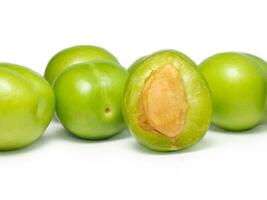 grön körsbär plommon på en vit bakgrund. frukt för framställning tkemali sås. diet mat. användbar frukter. saftig skära grön plommon foto