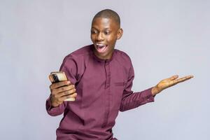 super Lycklig afrikansk kille i äkta kostym använder sig av mobil telefon fira Framgång över vit bakgrund, kopia Plats foto