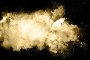 gyllene pulver explosion på svart bakgrund. frysa rörelse. foto