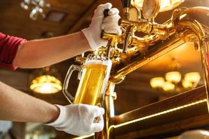 bartender händer hälla lätt öl i ett glas foto