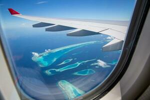 maldiverna ovanifrån från flygning med flygplansfönster. lyxsemestermål sett genom fönstret på ett flygplan. fantastiska maldivernas ölandskap och havslandskap. exotiska resekoncept foto