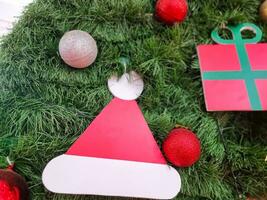 Lycklig ny år mysigt Hem interiör med jul träd och kransar små röd bollar och hatt gåva låda. suddig lampor gyllene bokeh.glad jul bakgrund. foto
