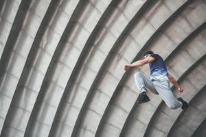 ung man gör parkourhopp i stadsrummet i stadens soliga vårsommardag. foto