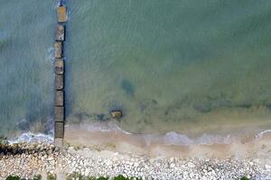antenn topp se från Drönare till de havsstrand med gammal betong pir foto