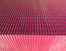 en hus med en röd tak tillverkad av korrugerad metall lakan. tak från korrugerad metall profil. metall kakel. foto