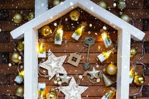 nyckel till hus med en Nyckelring mycket liten Hem på trä- bakgrund med jul dekor layout. gåva för ny år, jul. byggnad, projekt, rör på sig till ny hus, inteckning, hyra och inköp verklig egendom foto