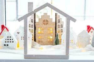 mysigt jul dekor mycket liten hus av små storlek på fönster tröskel med snö utanför de fönster. gåva för ny år. försäkring, rör på sig till ny hus, inteckning, hyra och inköp verklig egendom foto