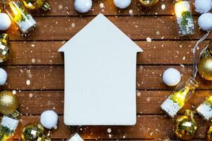 mycket liten vit hus falsk upp på trä- bakgrund med jul dekor layout och kopia Plats. gåva för ny år, jul. byggnad, projekt, rör på sig till ny hus, inteckning, hyra och inköp verklig egendom foto