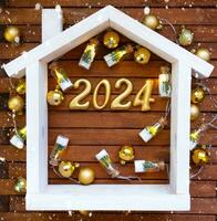 hus nyckel med Nyckelring stuga på festlig brun trä- bakgrund med stjärnor, lampor av girlanger. ny år 2024 trä- brev, hälsning kort. inköp, konstruktion, flytt, inteckning, försäkring foto