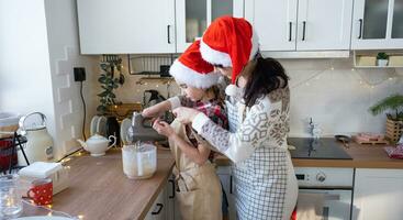 mamma och dotter i de vit kök knåda de deg i de skål för pepparkaka och småkakor med en blandare för jul och ny år. foto