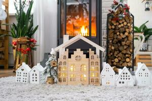 nyckel på jul träd och mycket liten hus på mysigt Hem med jul dekor nära de brinnande spis öppen spis. gåva för ny år. försäkring, rör på sig till ny hus, inteckning, hyra och verklig egendom foto