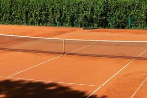 tennis domstol med en sand yta och en sträckt netto för spelar en sporter spel med en boll och racketar foto