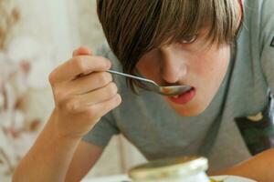 porträtt av en tonåring äter borscht med en sked. närbild foto