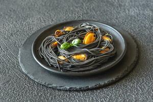 svart pasta med musslor och parmesan foto