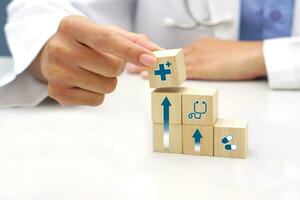 hand innehav en trä- blockera kub med sjukvård medicinsk ikon symbol. medicinsk och hälsa begrepp. foto