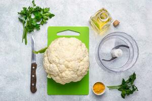 Ingredienser för matlagning blomkål ris och blandare skål på grå bakgrund foto