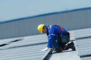 en tekniker är montera sol- paneler på de tak av de lager till förändra sol- energi in i elektrisk energi för använda sig av i fabriker. foto