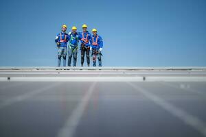 grupp av ingenjörer stående på sol- paneler med blå himmel i de bakgrund foto