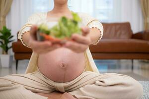 gravid kvinna äter färsk vegetabiliska sallad på Hem. graviditet begrepp foto